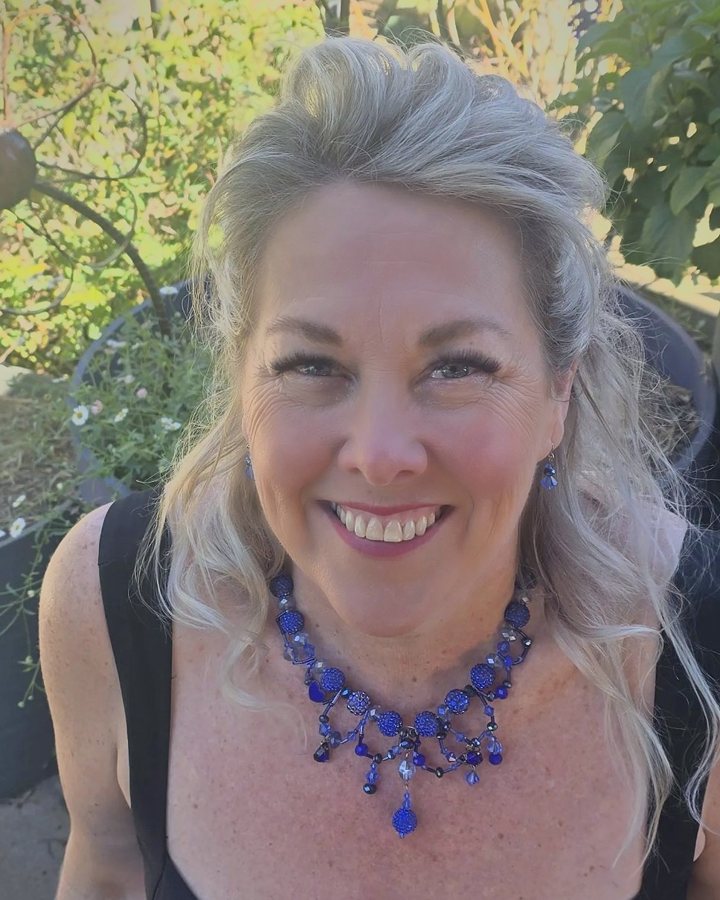 Dr Jennifer Hoysted in her garden wearing a cobalt blue Casni necklace and earrings
