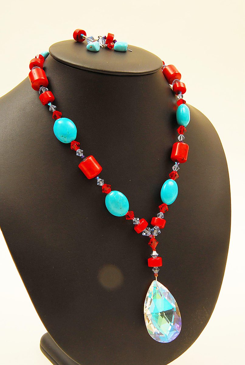 Red and turquoise necklace with a large crystal drop on a black bust
